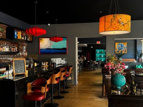 Shine dining room and bar with red lantern lighting and warm wood floors